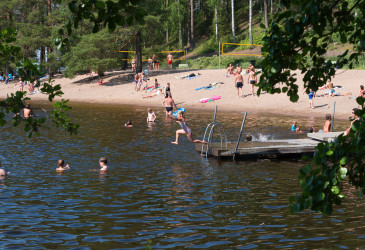 Ihmisiä kesähelteellä Ukonlinnan uimarannalla.