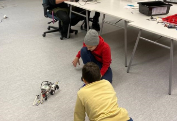 Kaksi lastaa tutkii robottia lattialla.