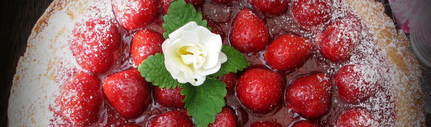 Mansikkakakku ylhäältä päin kuvattuna, kakun päällä on valkoinen ruusu. Kuva: Roine Piirainen / Kuvia Suomesta.